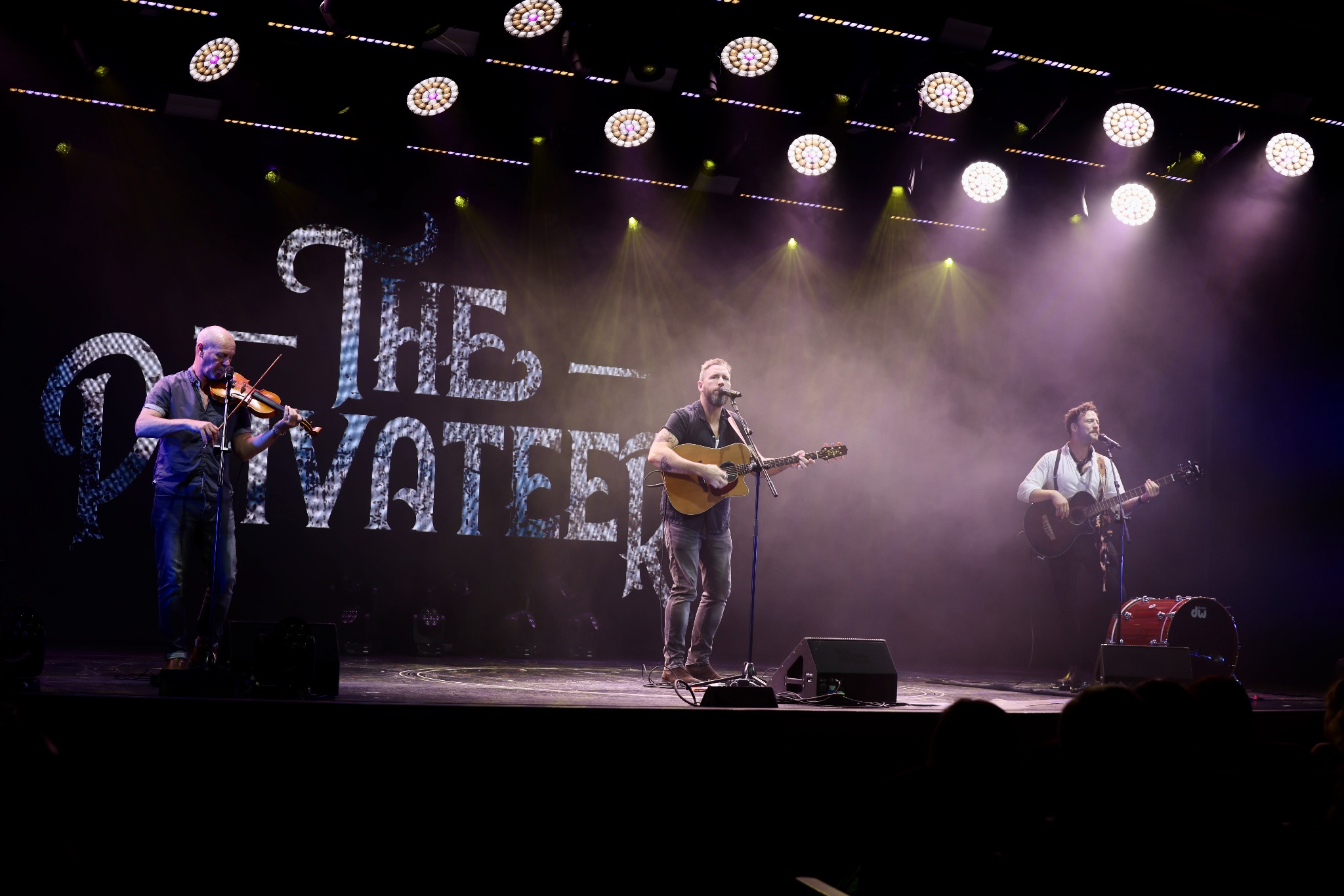 The Privateers performing together beneath stage lights